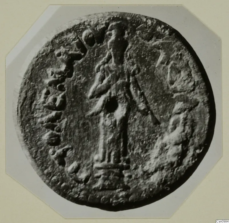 Round relief disc with a standing figure in the centre and raised marks around the edge, from Kountoura Trachonia