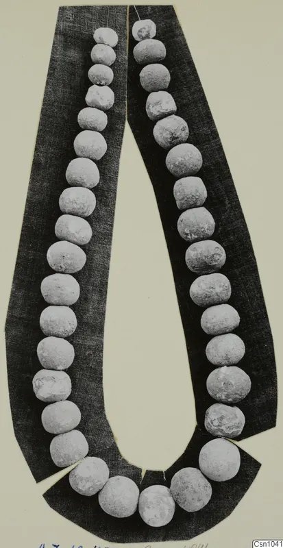 Necklace of pale, round beads laid in a long loop on a dark backing card