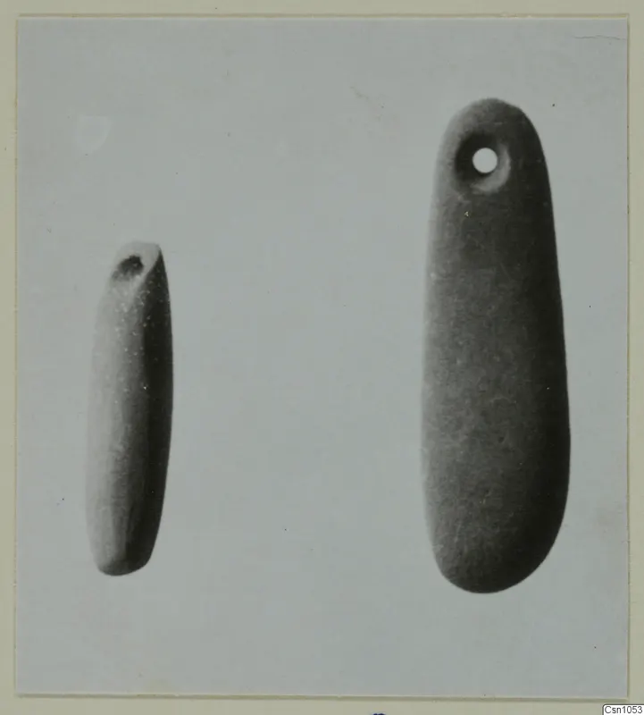 Two elongated, smooth pendants side by side, the larger with a drilled hole near its upper end.