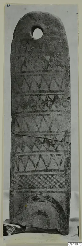 Tall flat terracotta object with a hole near the rounded top and dark painted zigzag and triangle patterns