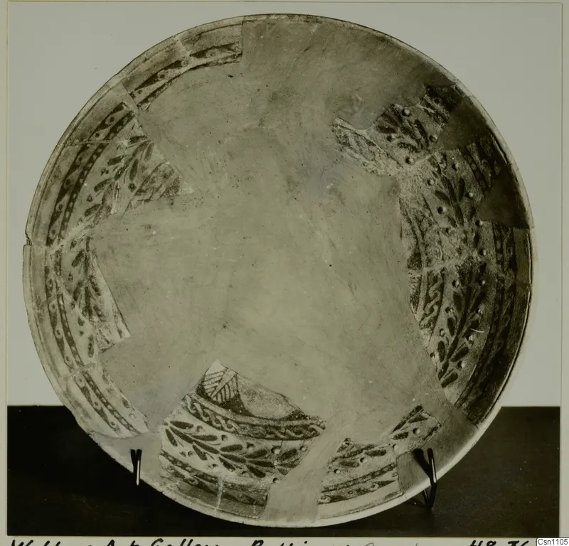 Faience bowl with dark painted leaf and dot bands around the rim, pieced together from fragments