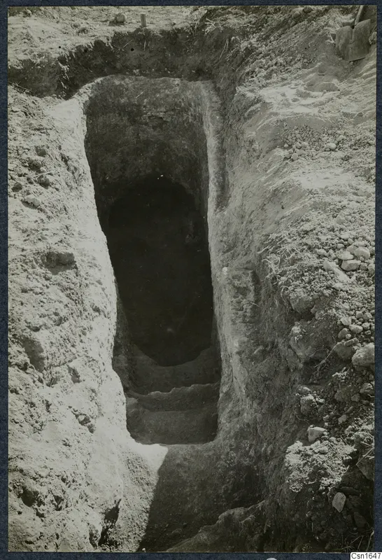 Excavated stepped cut at Ayios Iakovos leading down to a dark opening, with stones along the edges