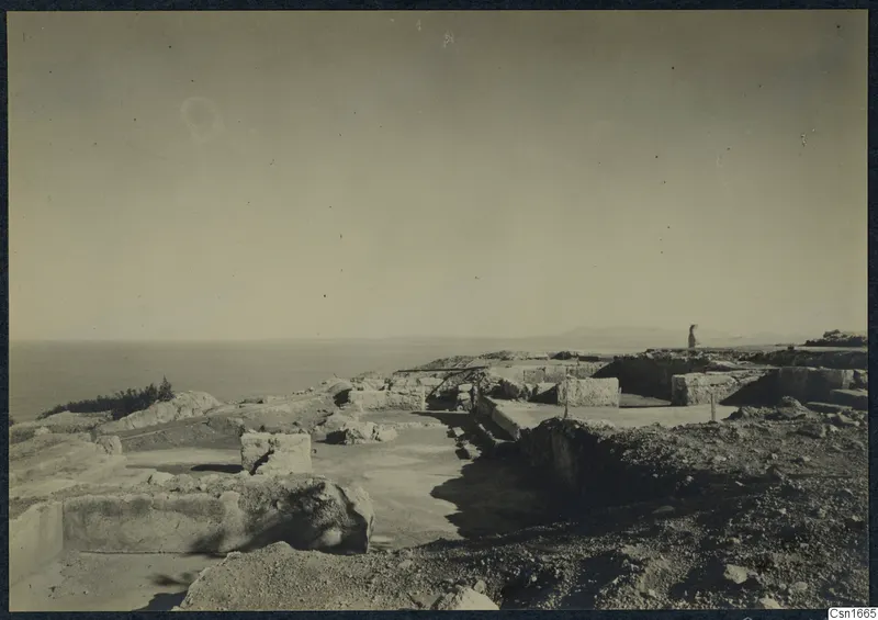Ruins of Vouni Palace on a rocky headland, with stone walls and blocks and the sea beyond