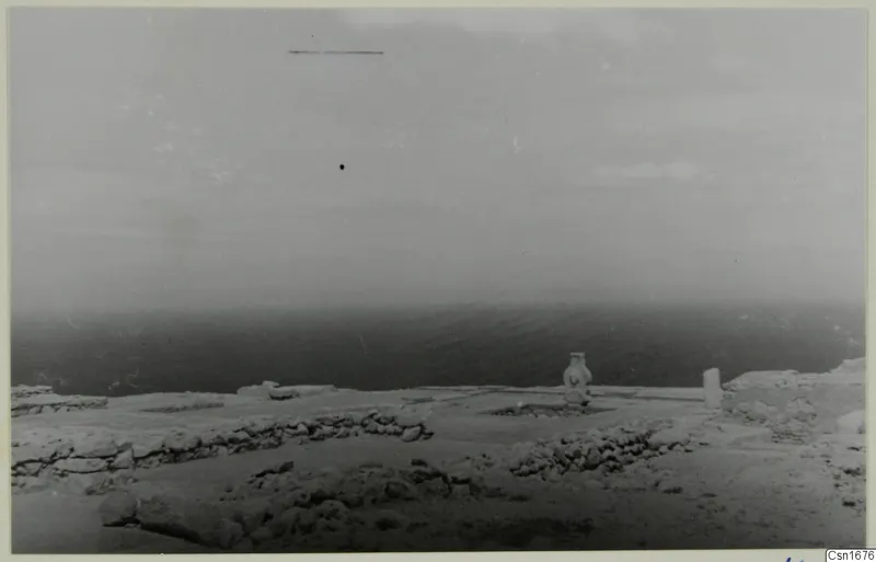 Low stone walls and cleared ground on the hilltop at Vouni, with the sea beyond