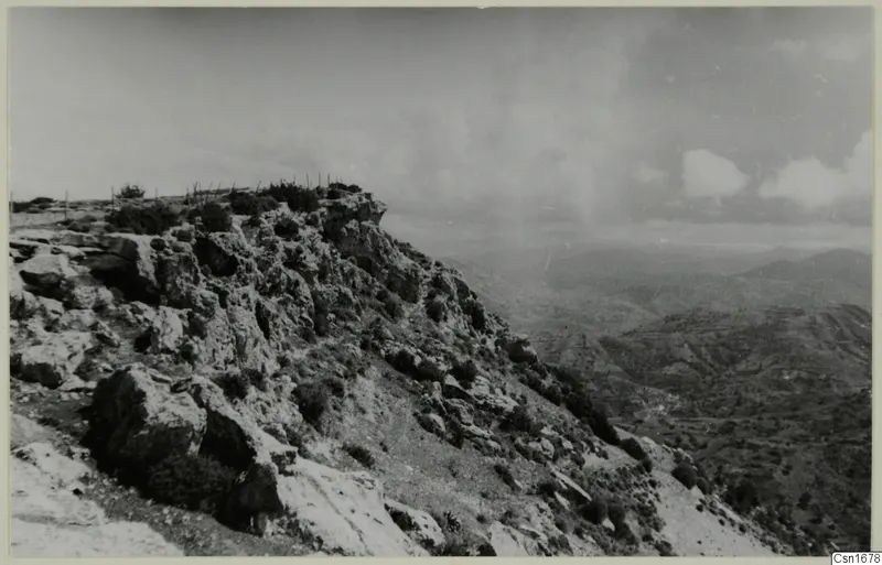 Rocky hilltop at Vouni with scrubby bushes, looking out over a valley of hills and terraced slopes.