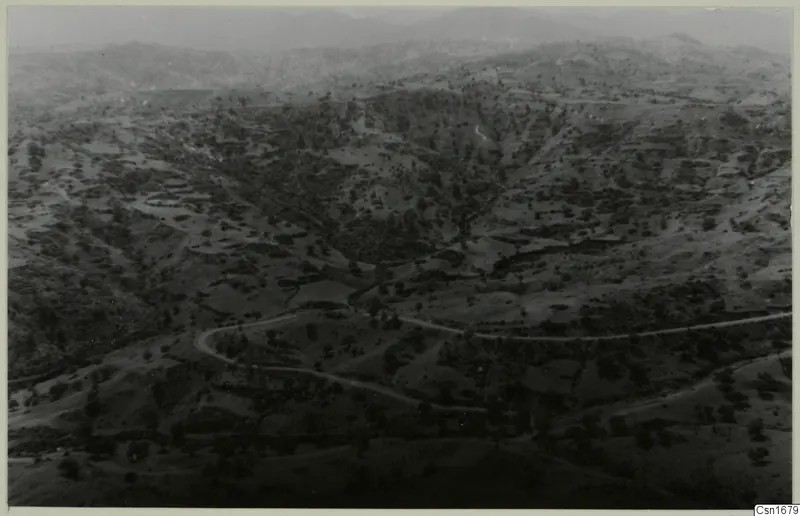 Wide view over hilly, wooded country with a winding road, taken from high above the palace site at Vouni.