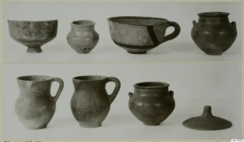 Group of vessels from Marion in two rows, including a cup-like bowl with a dark painted band, two jugs and a domed lid