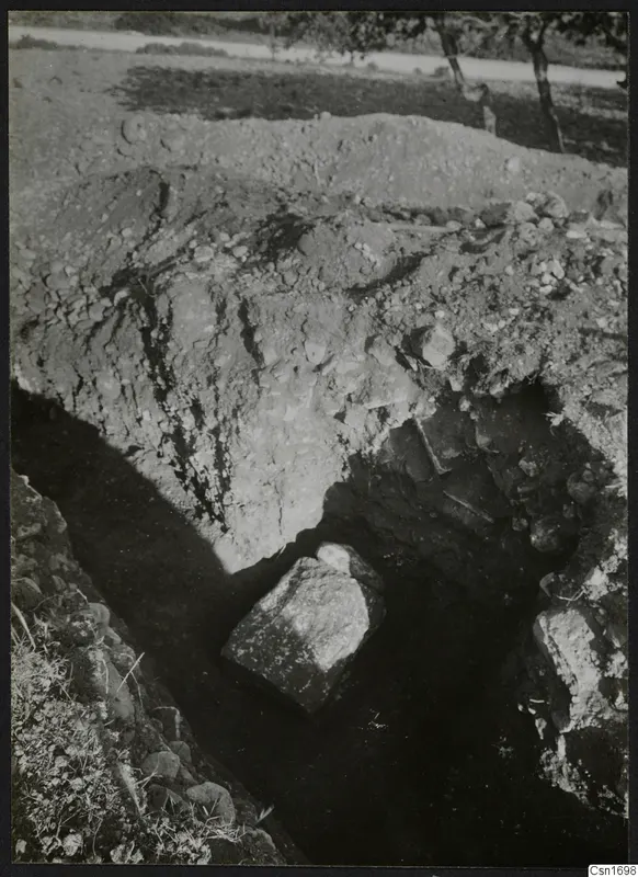 Excavation trench at Amathus with a large stone block, spoil heap and trees in the background