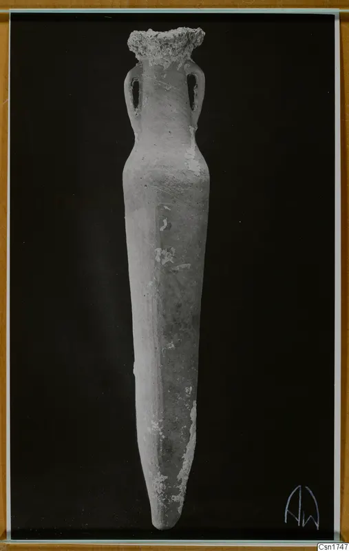 Tall pottery vessel with two loop handles and a pointed base, photographed upright against a black background