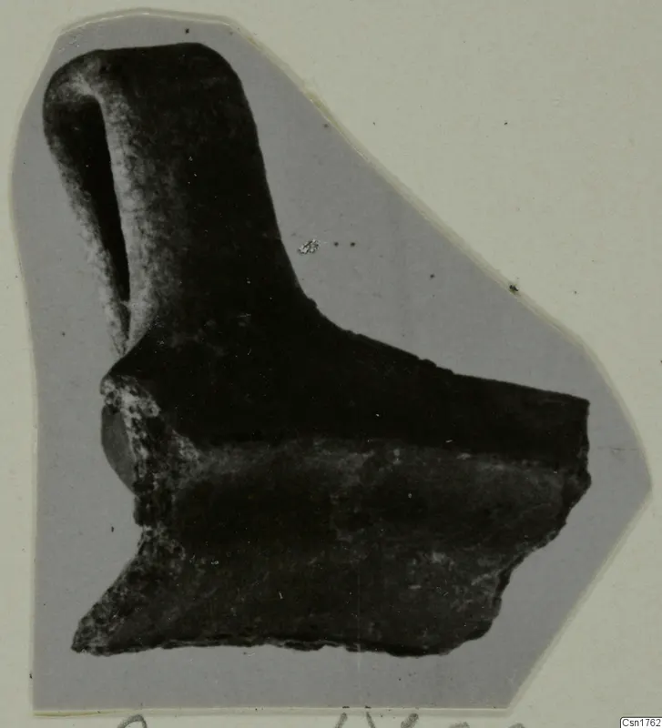 Broken pottery sherd with a tall, narrow projection rising from a thicker body fragment, shown on a grey card mount