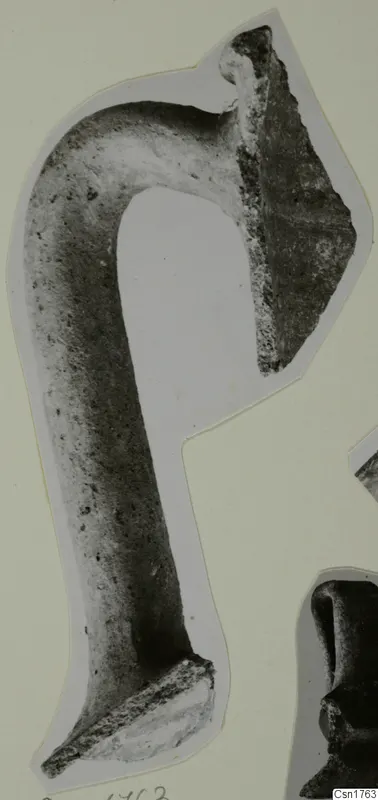 Pottery fragment with a long curved arm and a broken angled edge, mounted on a pale card.