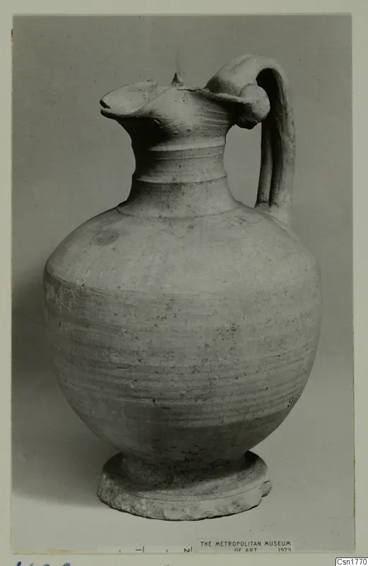 Pottery jug with a pinched spout, single strap handle and ring foot, shown against a grey background