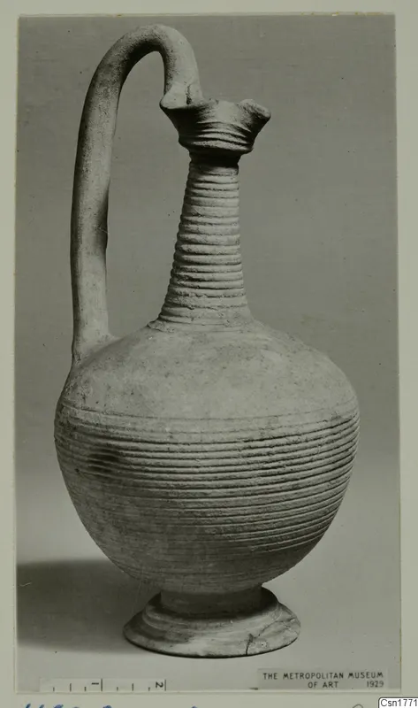 Pottery jug with a tall ribbed neck, flared mouth, strap handle and globular body, standing on a ring foot.