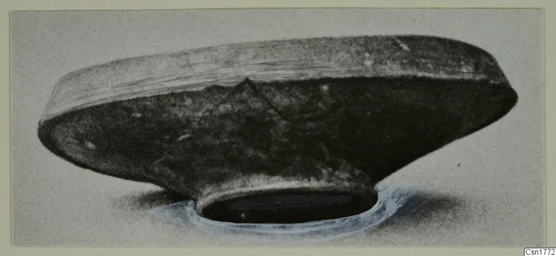 Dark, shallow vessel with a wide body and narrow ring foot, photographed from the side.