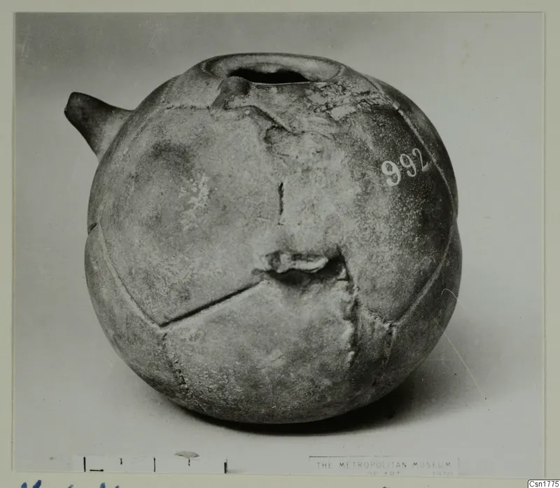 Globular vessel with a short spout on the left and a wide-rimmed opening at the top, photographed on a grey backdrop.