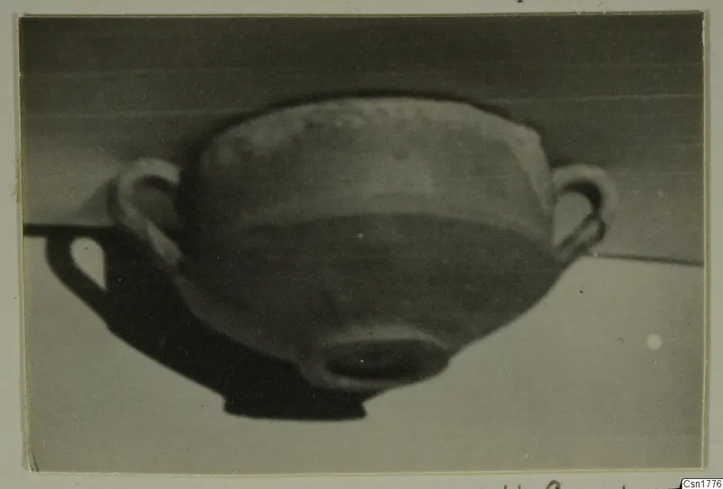 Two-handled bowl photographed at an angle on a pale surface