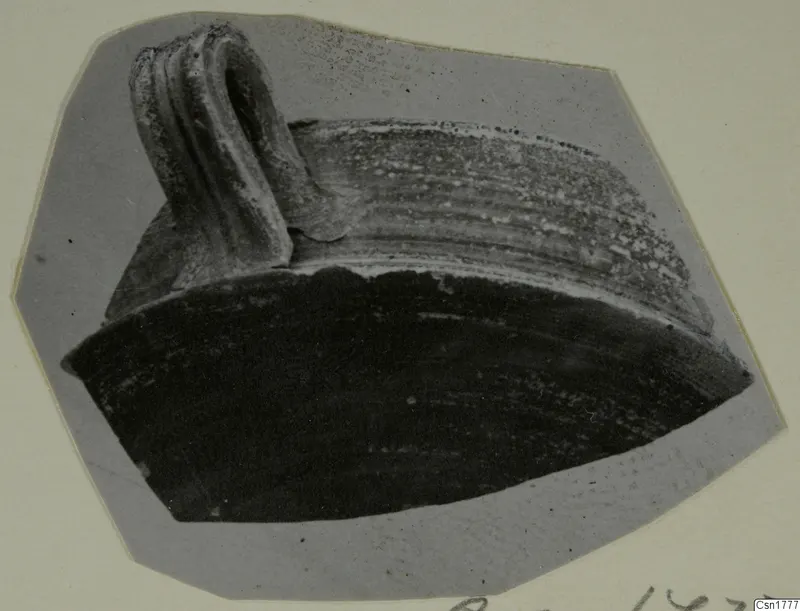 Fragment of a pottery vessel with a ribbed strap handle, shown on a grey card mount.