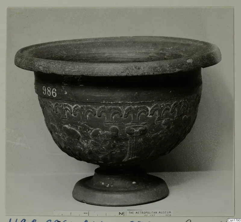 Footed bowl with a flaring rim and raised ornament around the body, photographed against a pale backdrop