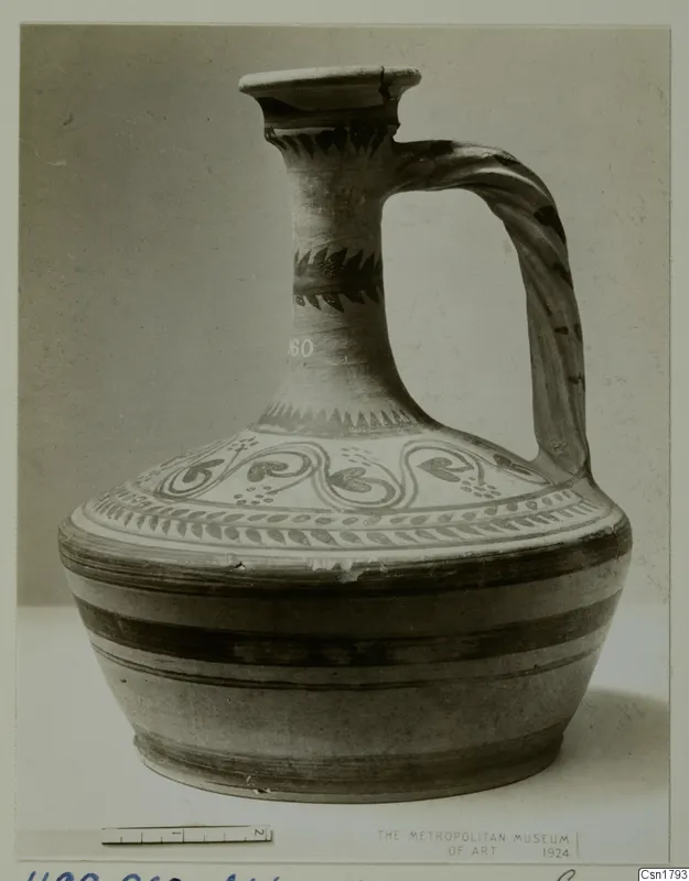Painted jug with a tall neck, flared mouth and strap handle, shown against a grey backdrop