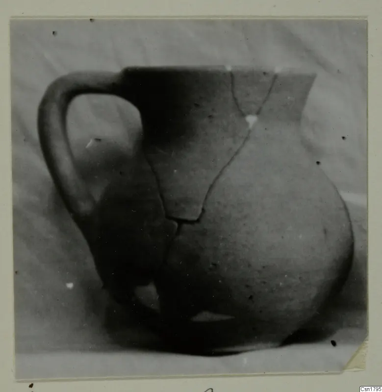 Cypro-Hell. II pottery jug with a single handle, cracked and partly broken, against a plain background