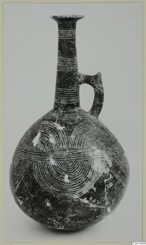 Red Polished III jug from Vounous with a tall neck, loop handle and incised concentric arcs on the body