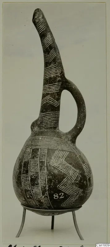 Red Polished III jug with a tall tapering neck, strap handle and white chevron and band decoration, on a metal stand