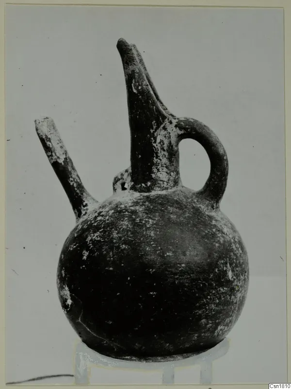 Red Polished III jug with a tall spout, a side spout and a loop handle, shown on a stand