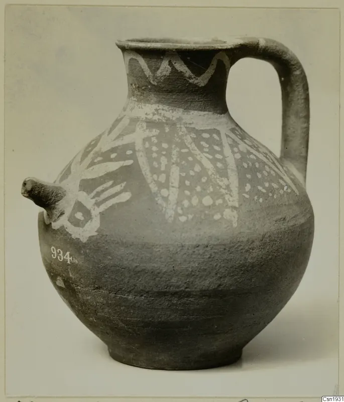 Jug with a spout and strap handle, decorated with white painted bands and pattern on a dark surface