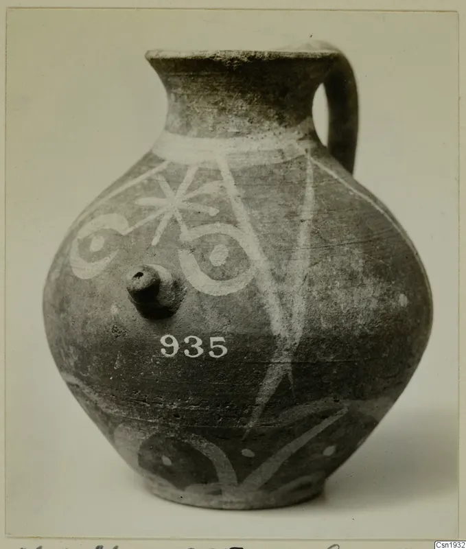 Painted pottery jug with a strap handle, white decoration on a dark surface
