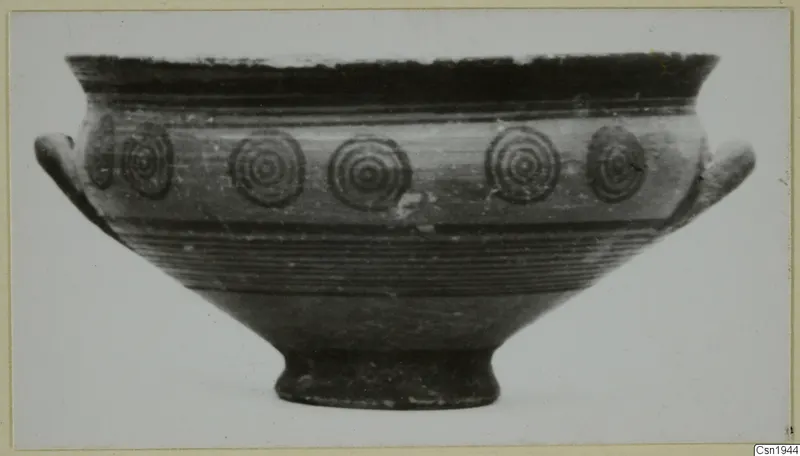 Painted bowl with two side handles and a band of concentric circles on its body, shown in side view