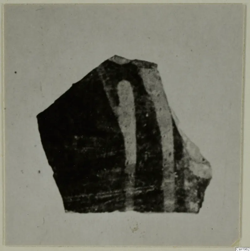 Pottery sherd with a dark surface and two pale curving bands, photographed on a grey card.