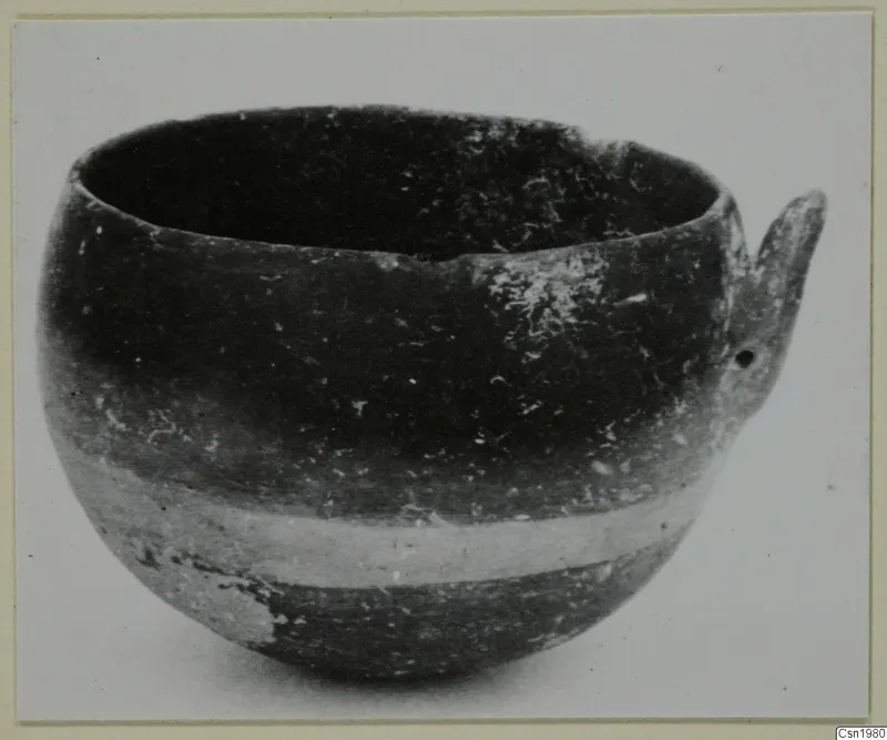Pottery Reserved Ware bowl from Vounous with a single handle, photographed and mounted on a card.