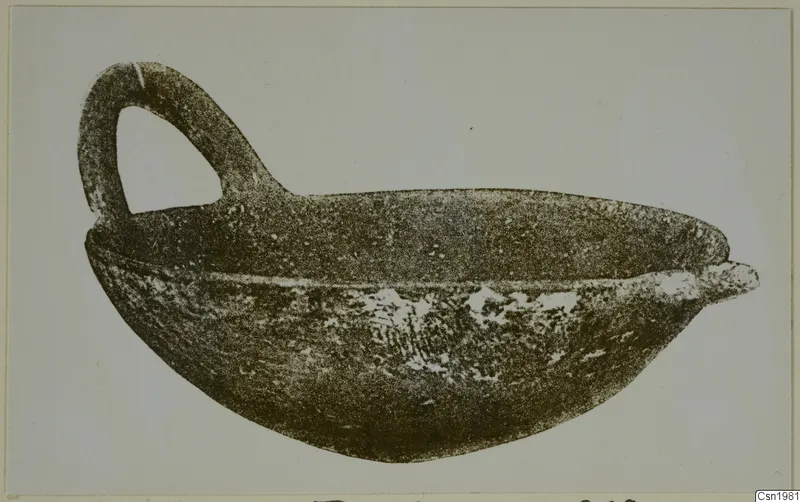 Pottery Red Polished IV: a bowl with a single loop handle, shown in side profile against a plain background.
