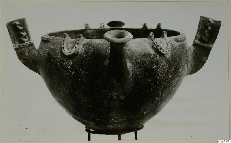 Red Polished III bowl from Vounous, with two large side lugs, a central spout and small knobs on the rim, set on a metal stand.