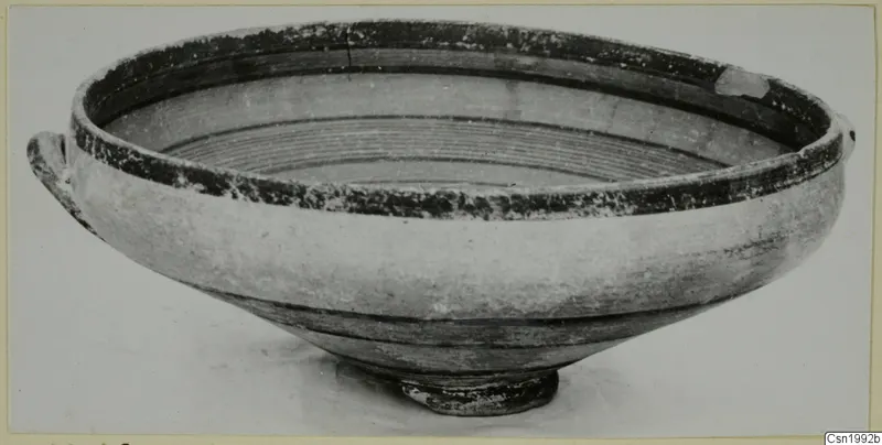 Pottery bowl with two small handles and dark painted bands around the rim and interior, shown on a plain background