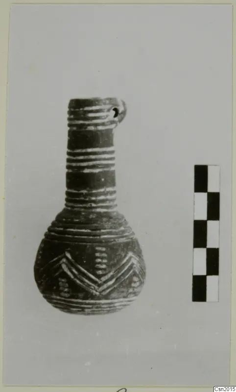Pottery vessel with a narrow neck, a pierced lug at the rim and light banded and chevron decoration, beside a scale bar