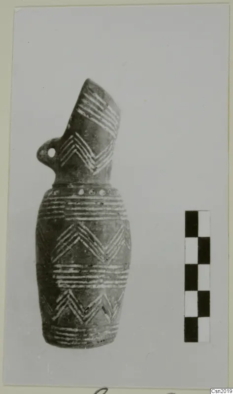 Pottery vessel with a tall spout, loop handle and white painted chevron and band decoration, shown beside a scale bar.
