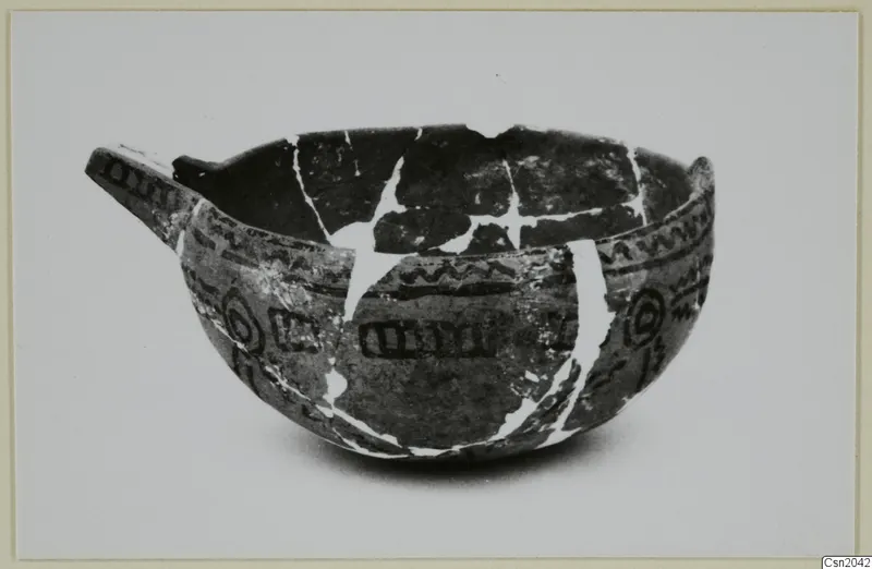 Pottery bowl with one handle, dark painted bands, zigzags and concentric circles, its breaks joined with pale lines