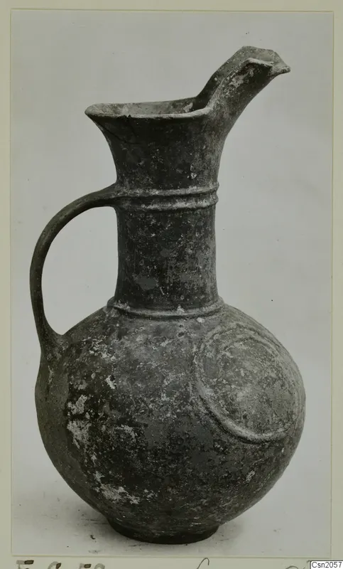 Pottery Base-Ring Ware jug with a pinched spout, a loop handle and a raised arc motif on its body.