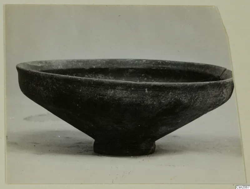Shallow bowl with a flared rim and short ring foot, dark surface, photographed from the side