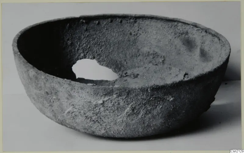 Large rounded bowl with a thick, rough grey surface, photographed from the side and slightly above.