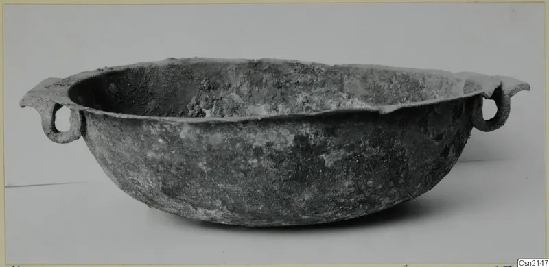 Corroded metal bowl with two ring handles, from Marion tombs 31–45