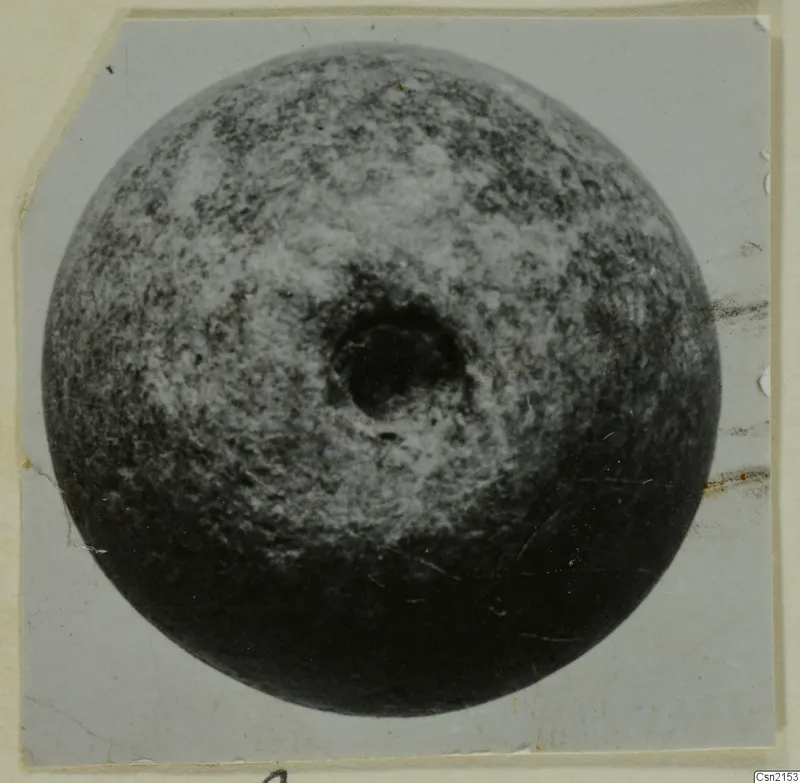 Round object with a central hole, seen from above, mounted on a pale grey card