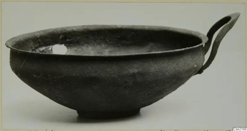 Dark grey bowl with a single strap handle and a ring foot, photographed from the side.