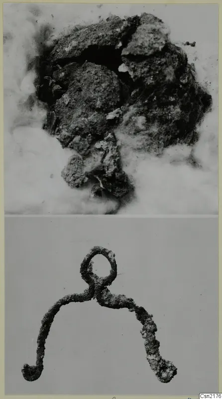 Corroded metal objects: an encrusted mass above and a looped, hooked metal piece below.