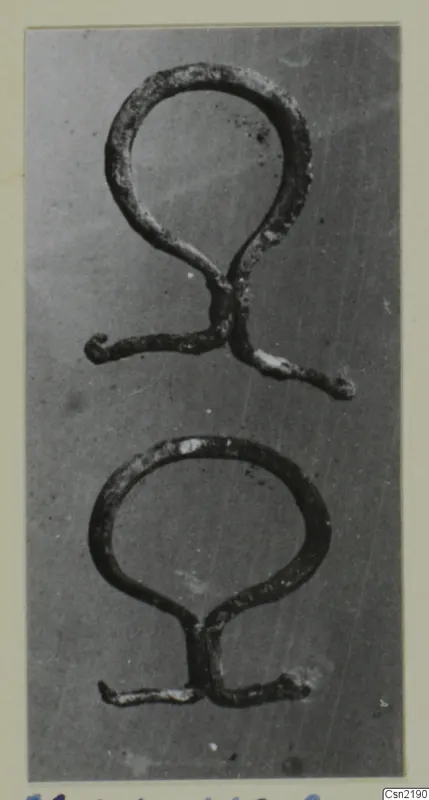 Two bronze loop-shaped mountings or handles from Marion, photographed on a grey background