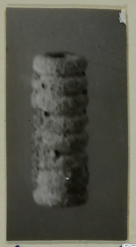 Blurred close view of a cylindrical object with horizontal ridges against a dark grey backdrop