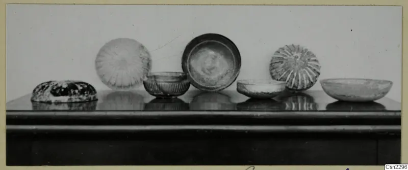 Several blown glass bowls and dishes standing in a row on a dark table