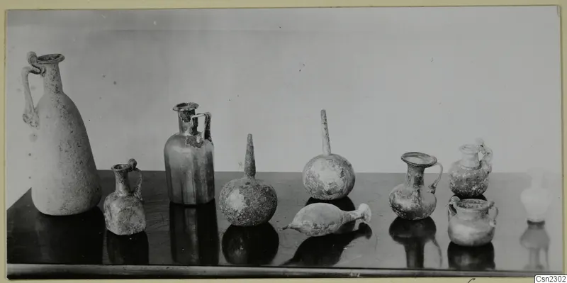 Group of blown glass jugs, jars and flasks with handles on a dark table