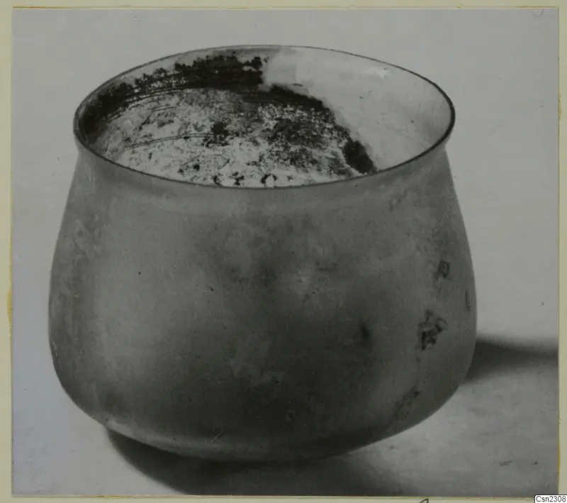 Blown glass jar with a wide, flared rim and weathered surface, shown on a plain surface.